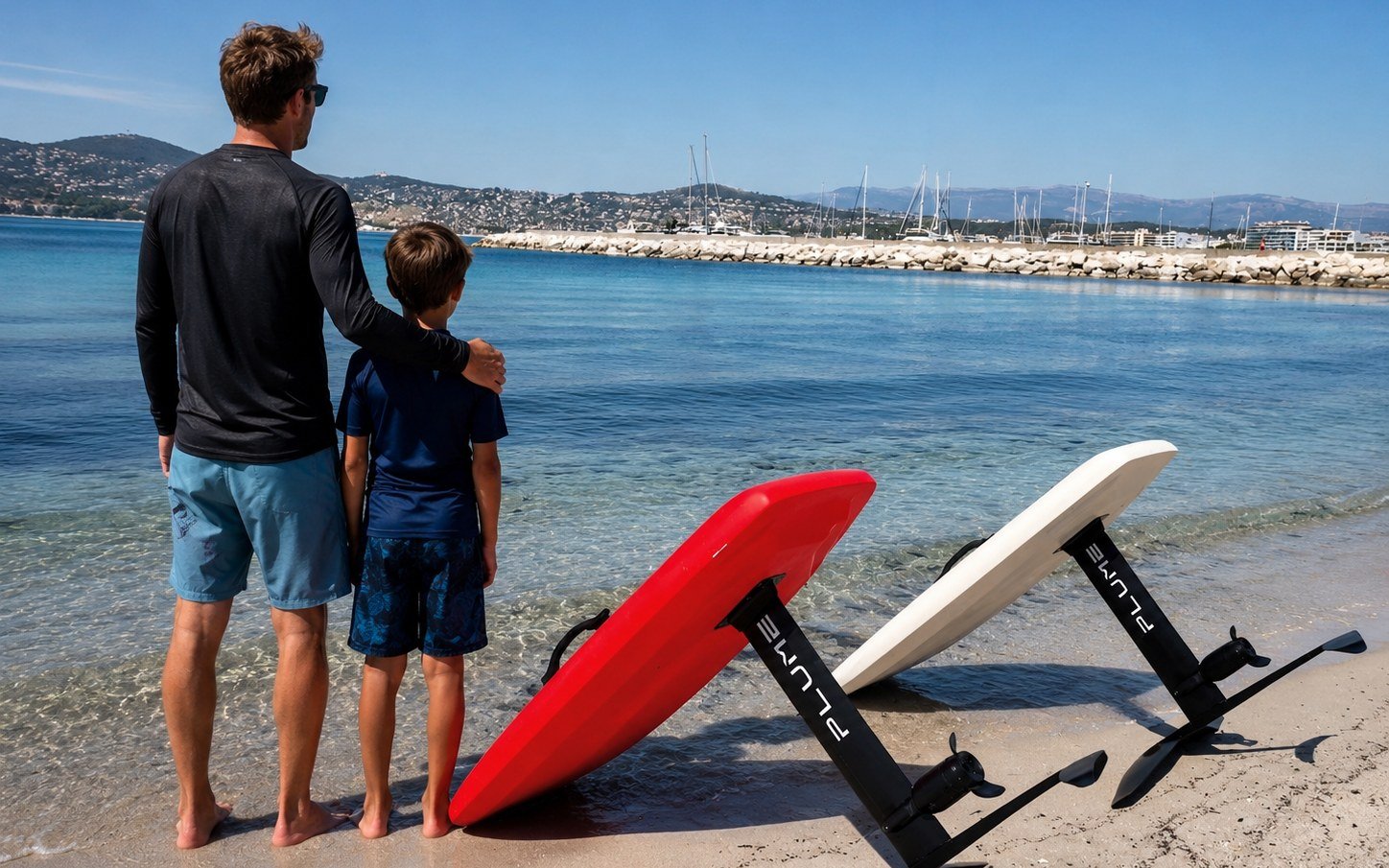 Father and son facing the sea with two Plume eFoil boards, red and white